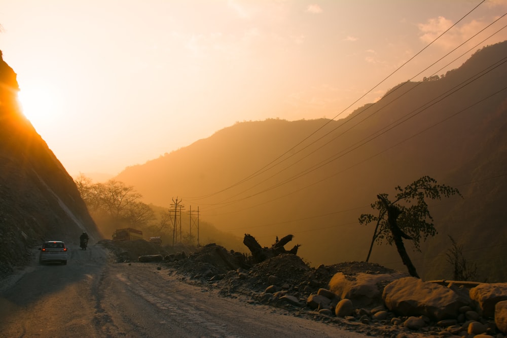 a car driving down a dirt road next to a mountain