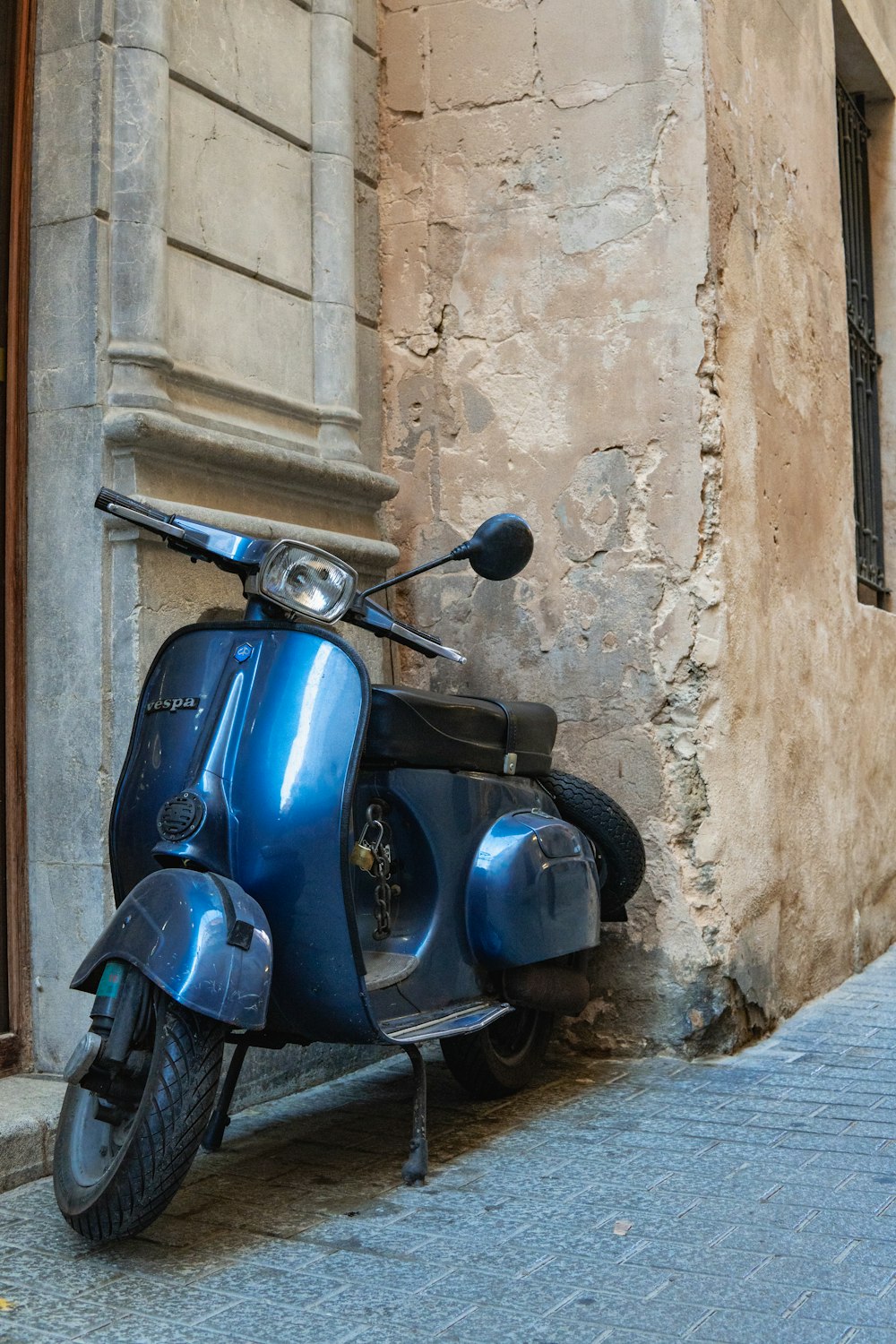 a blue scooter parked on the side of a building