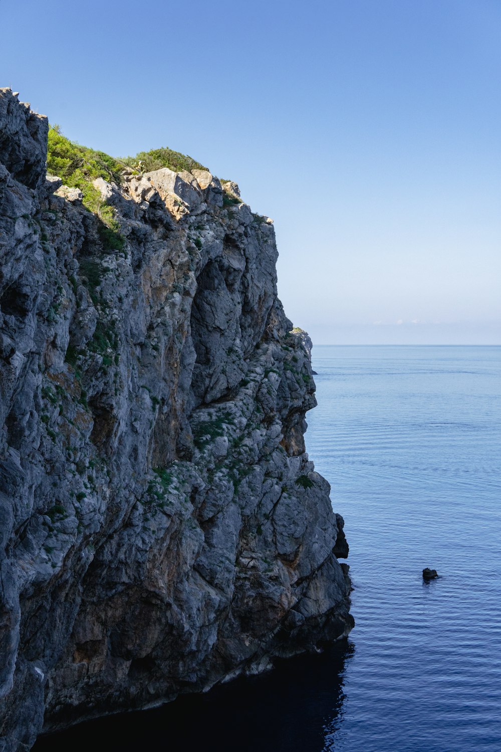 a rocky cliff with a body of water in the foreground