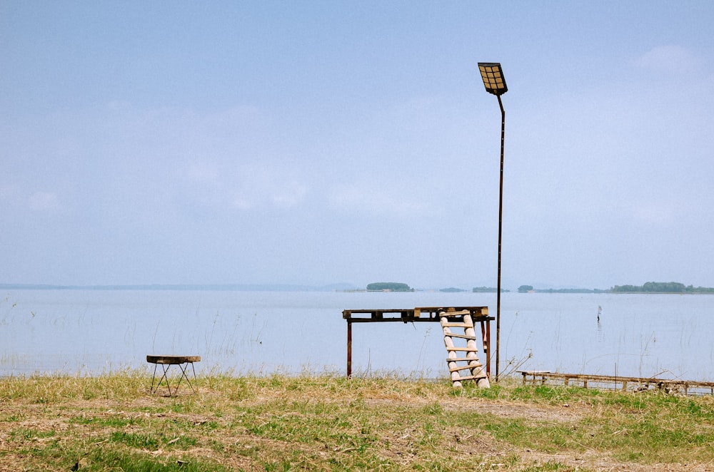 a bench and a lamp on the shore of a lake