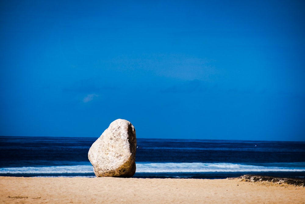 a large rock sitting on top of a sandy beach