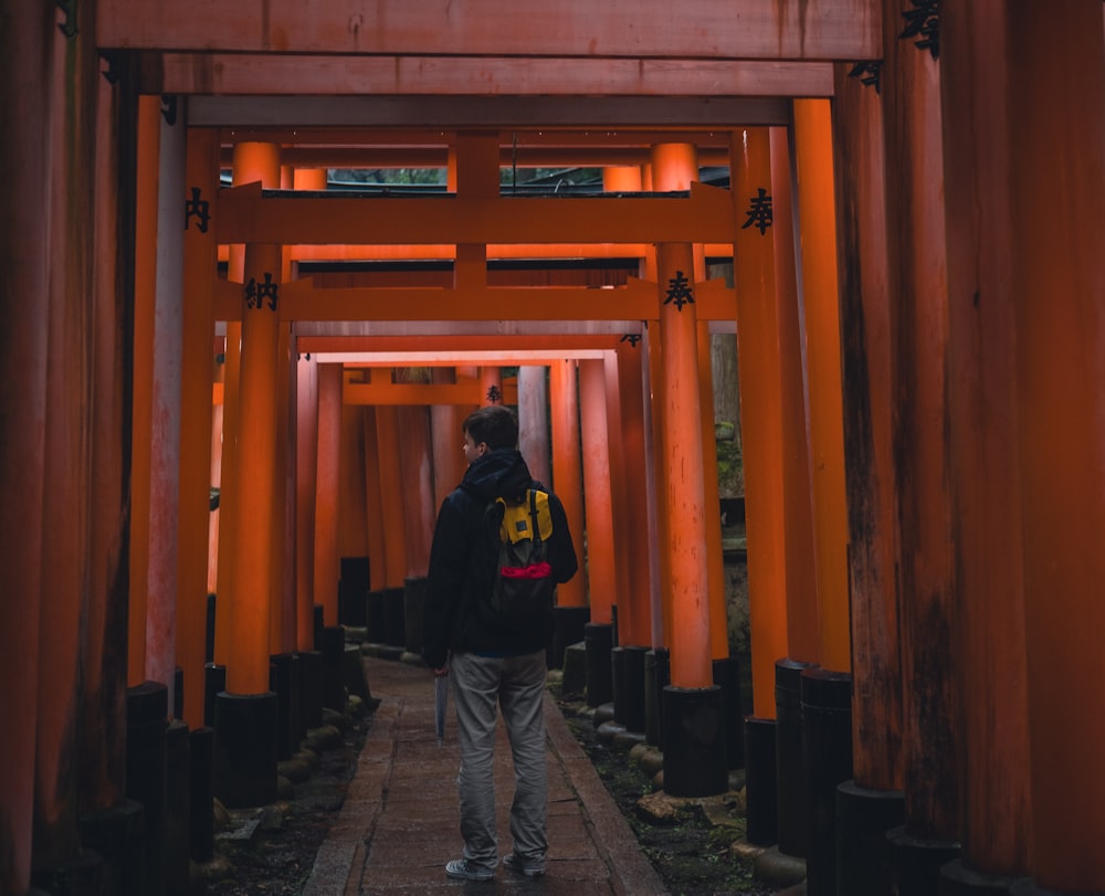 um homem com uma mochila andando por um túnel de Orange Tori Tori Tori Tori Tori