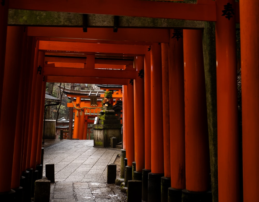a walkway lined with orange pillars and lanterns