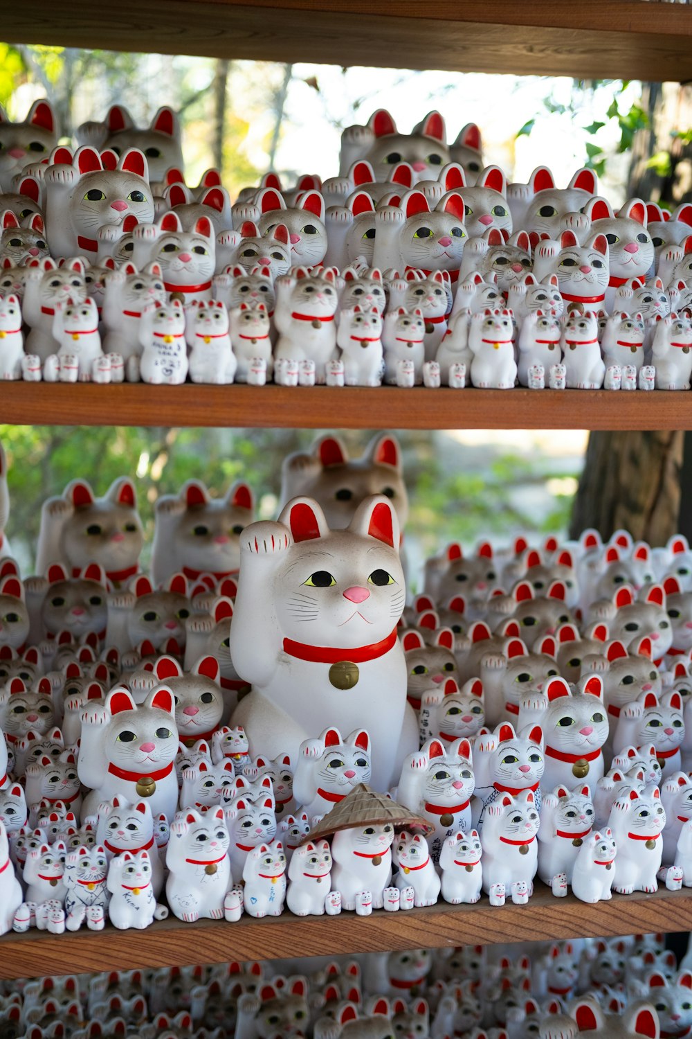 Un estante lleno de muchas figuritas de gatos blancos y rojos