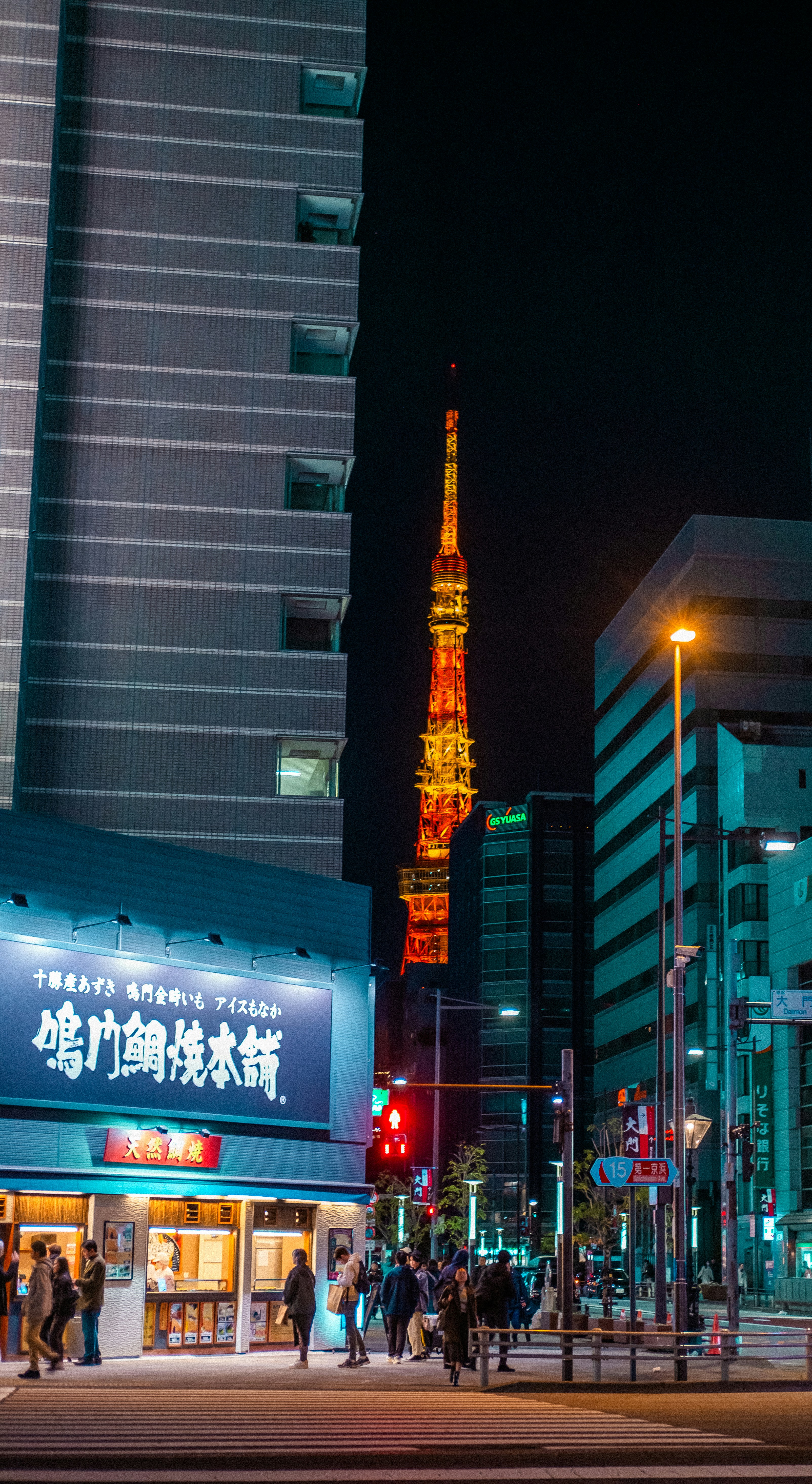 Un grupo de personas caminando por una calle junto a edificios altos