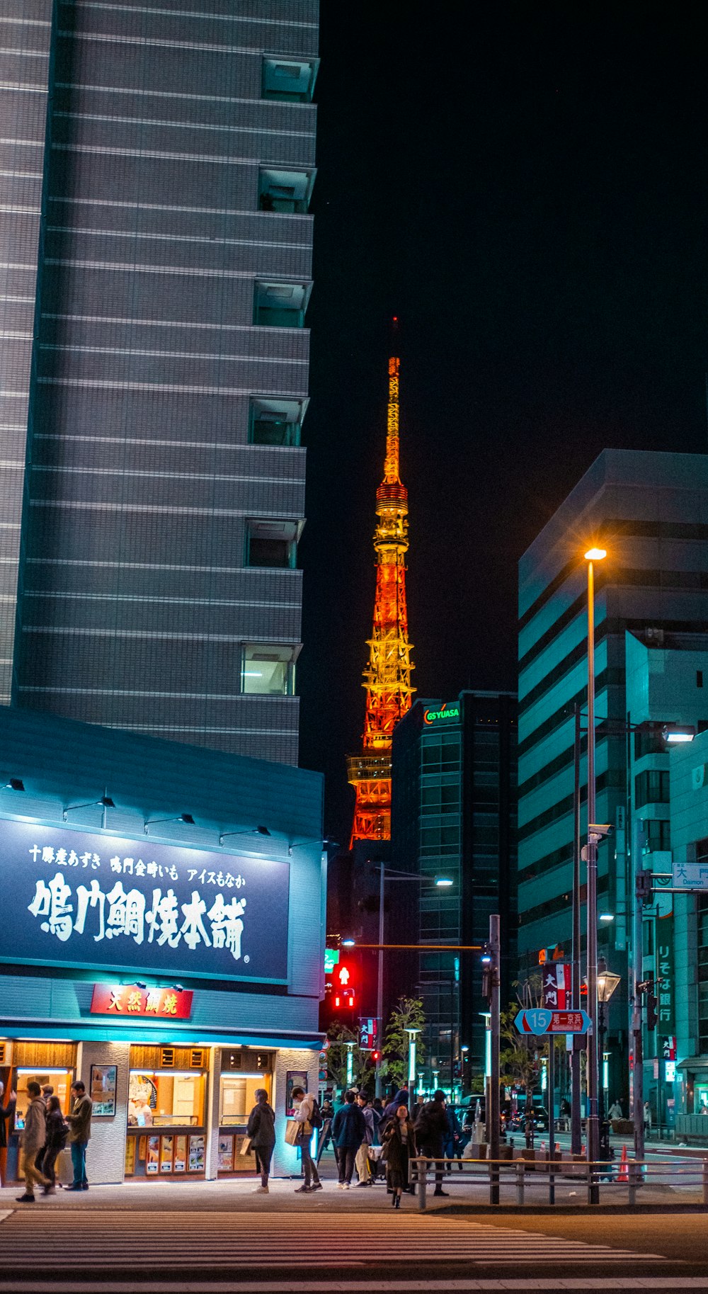 a group of people walking down a street next to tall buildings