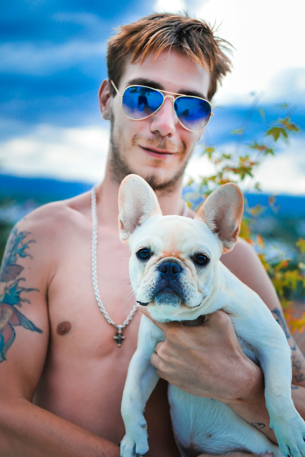 a shirtless man holding a small white dog