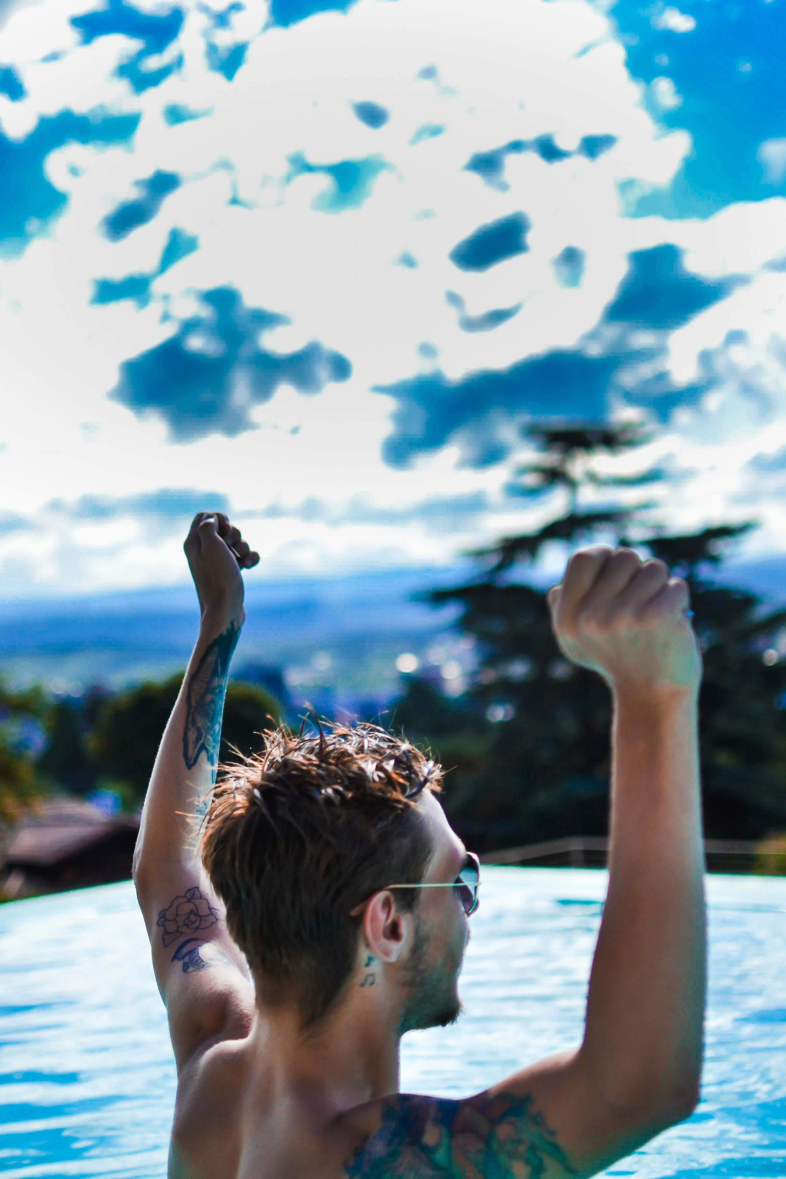 A man in a swimming pool raising his arm in the air photo – Free Blue ...