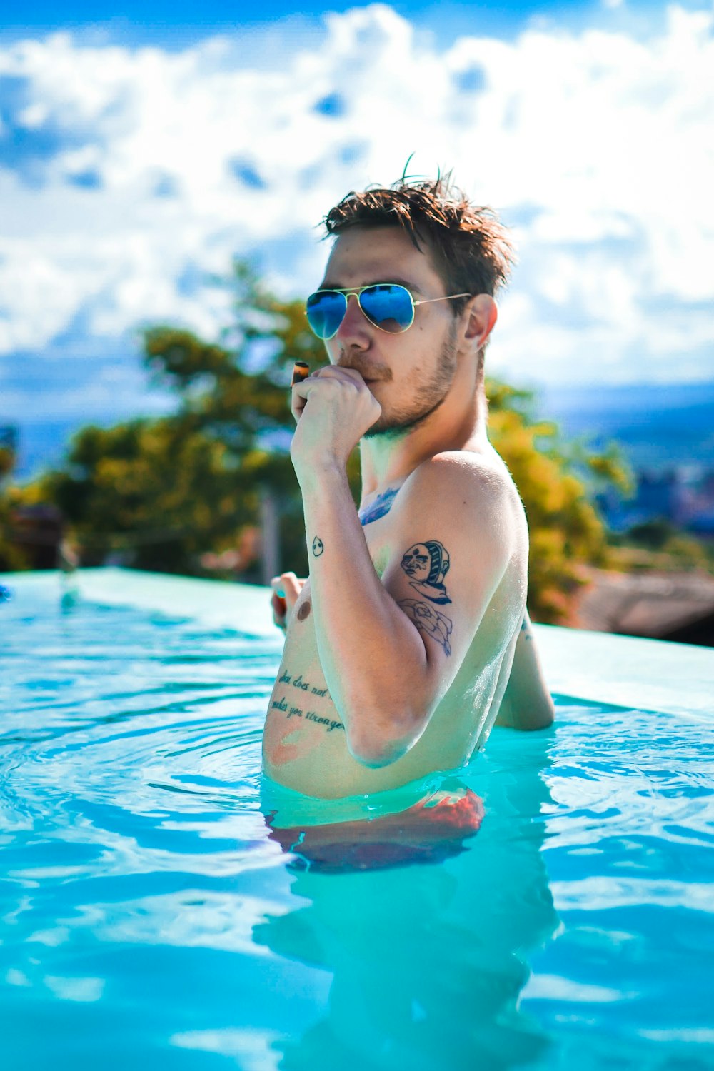 a man sitting in a pool with a cigarette in his mouth