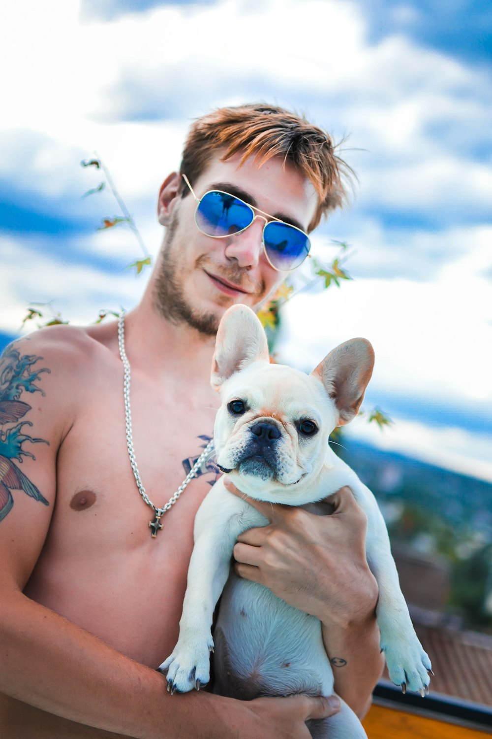 a shirtless man holding a small white dog