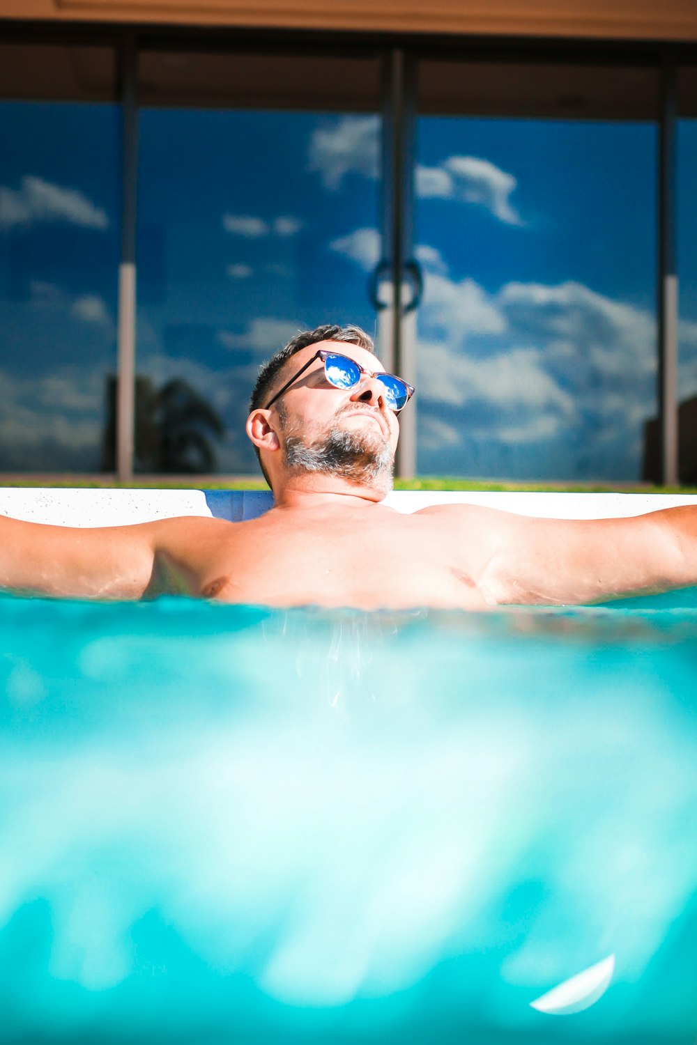 a man laying in a swimming pool wearing sunglasses