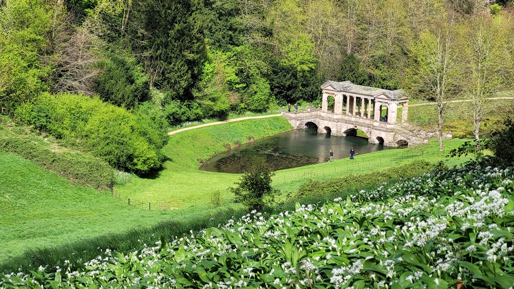 a stone bridge over a pond in a lush green park