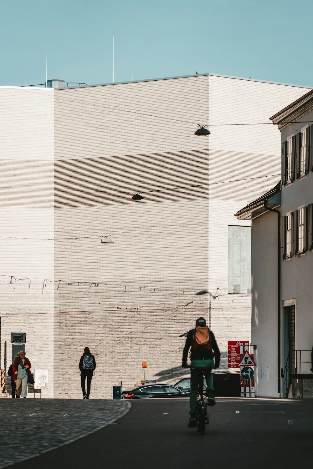 a man riding a bike down a street next to a tall building