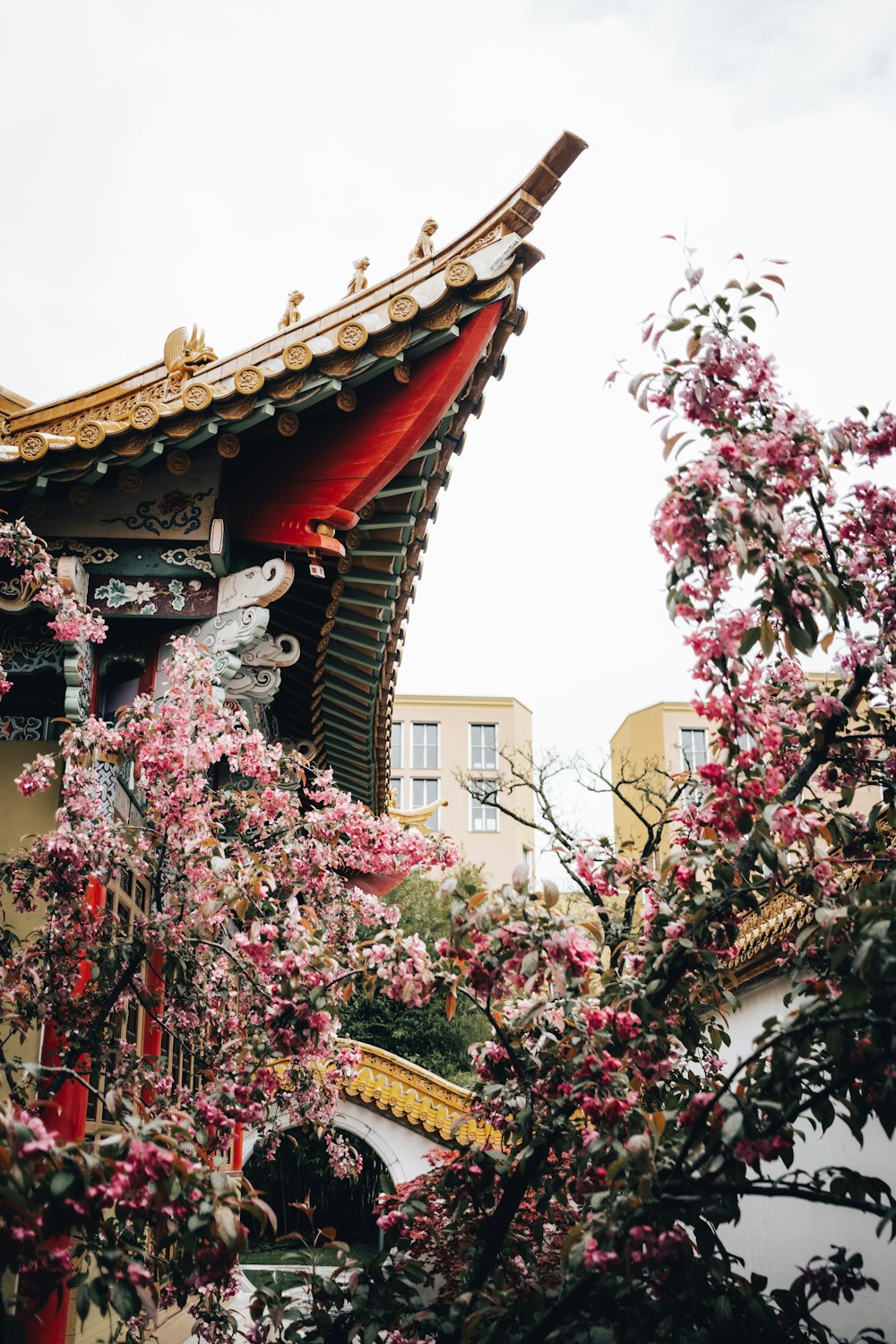 a building with a red roof surrounded by pink flowers