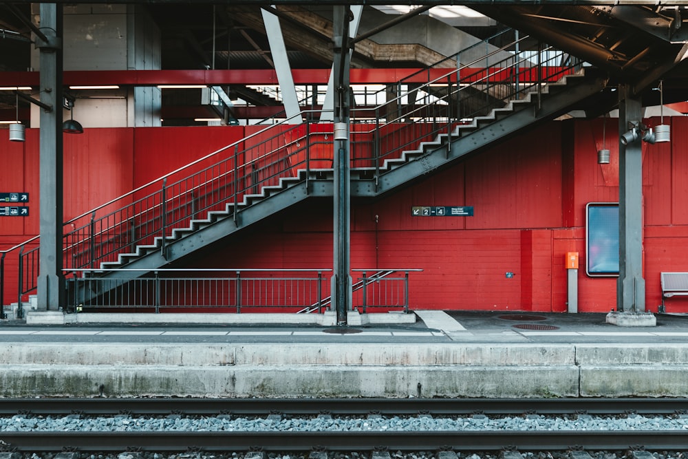 una estación de tren con un muro rojo y escaleras