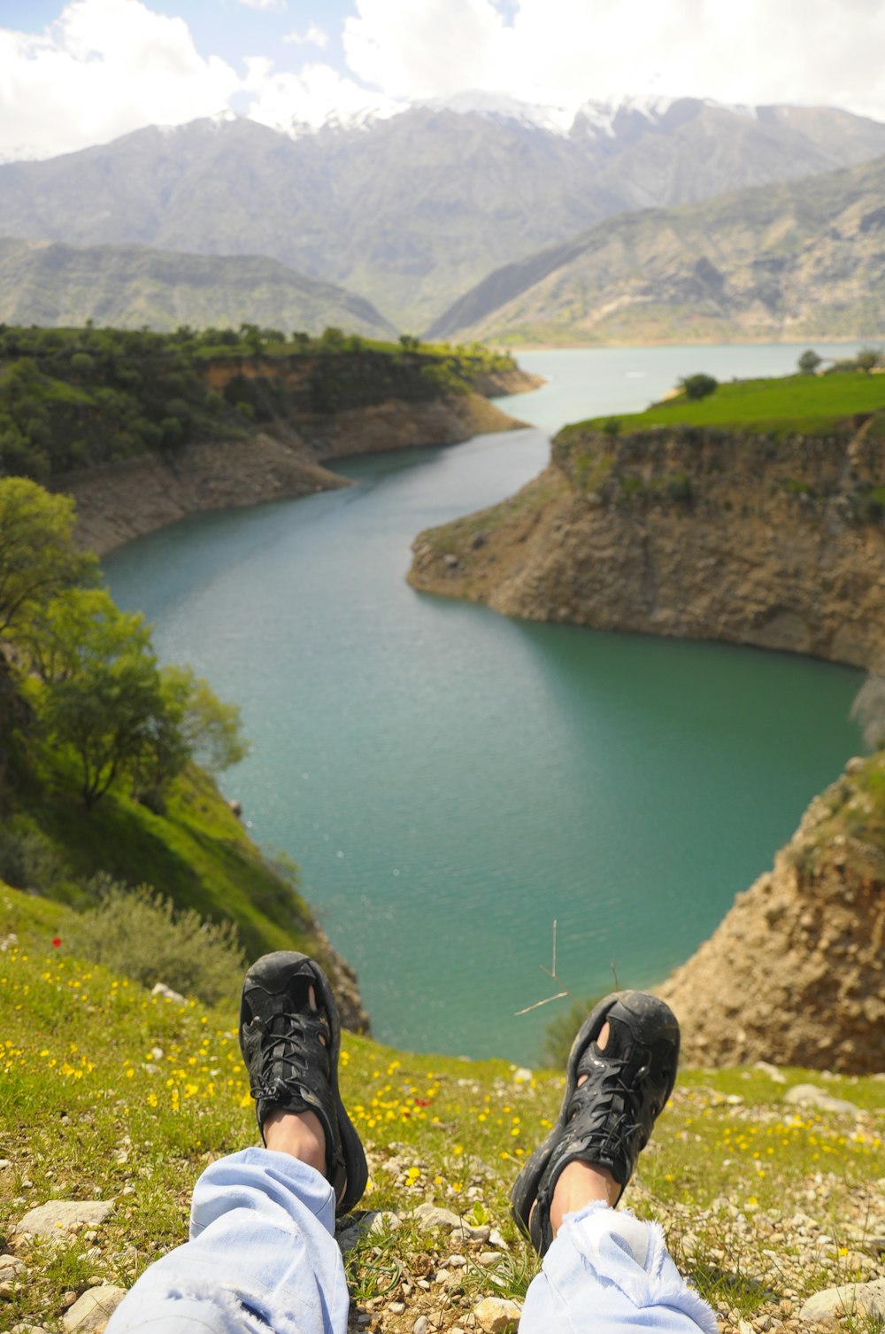 une personne avec les pieds sur une colline surplombant un lac