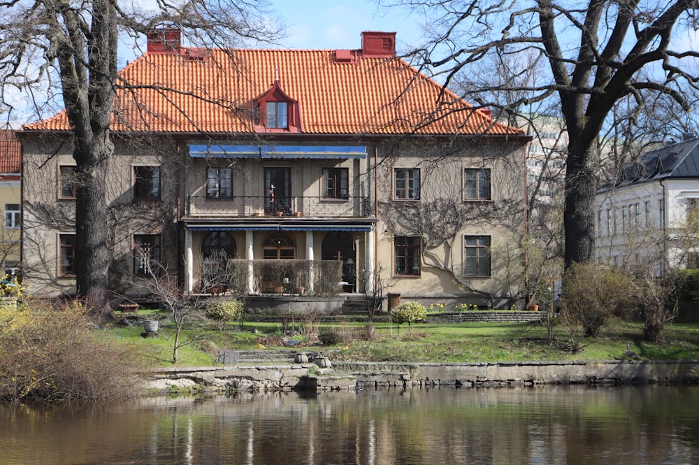 a house with a red roof next to a body of water