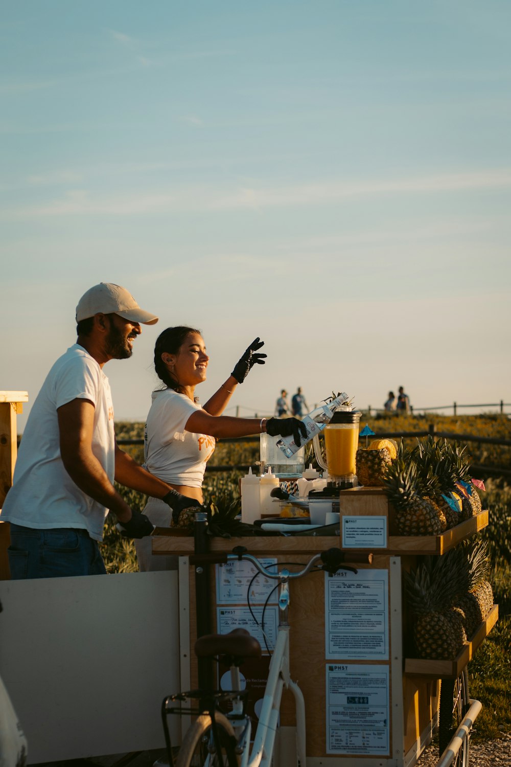 a man and a woman standing at a table with pineapples