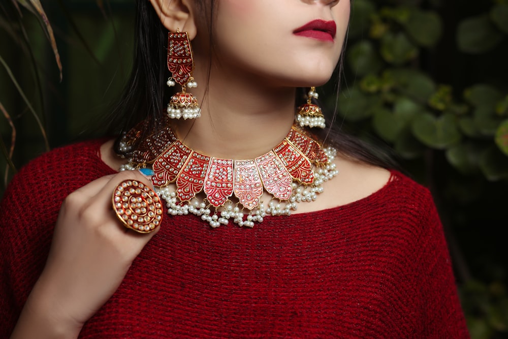a woman in a red sweater wearing a necklace and earrings