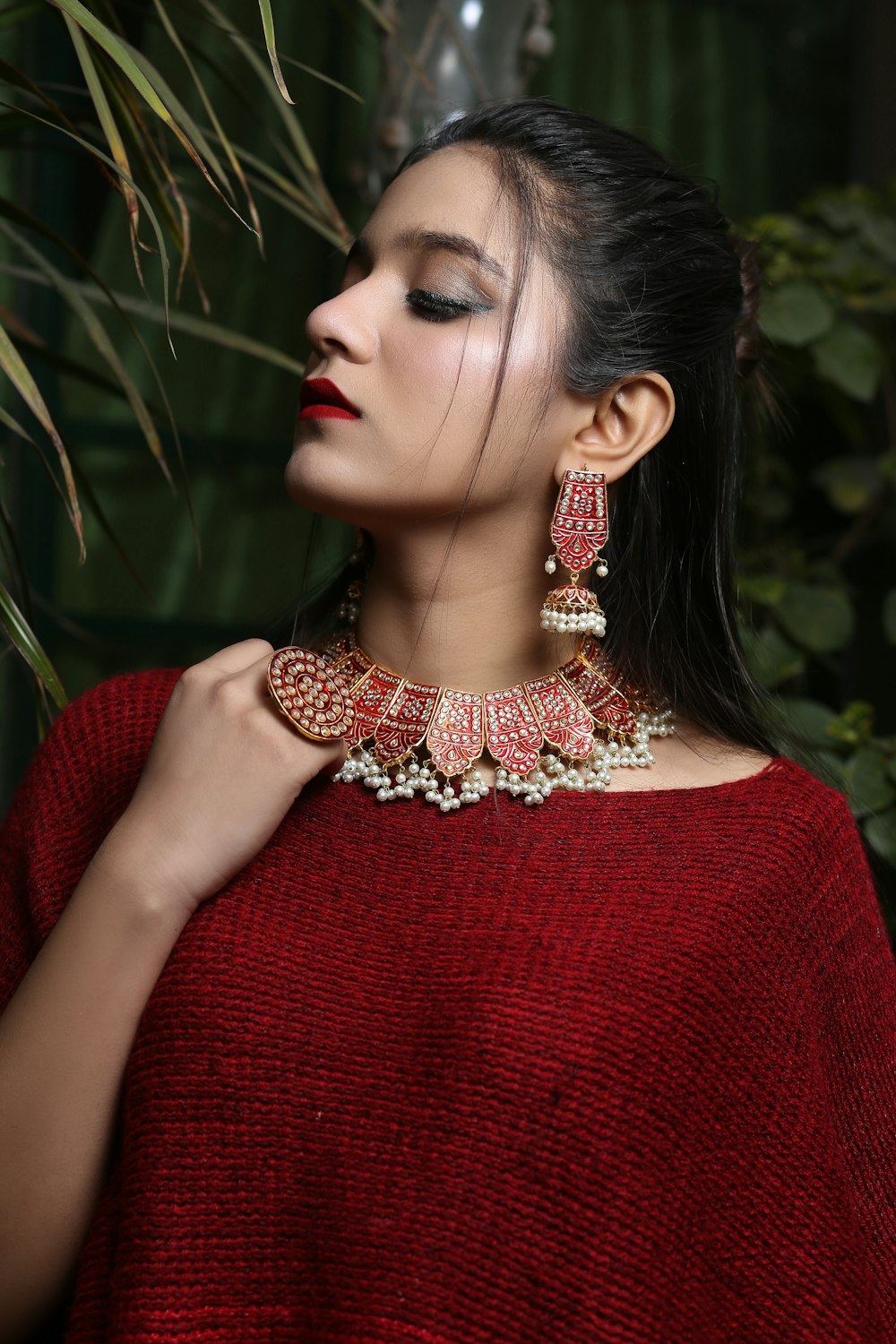 a woman wearing a red sweater and a pair of earrings