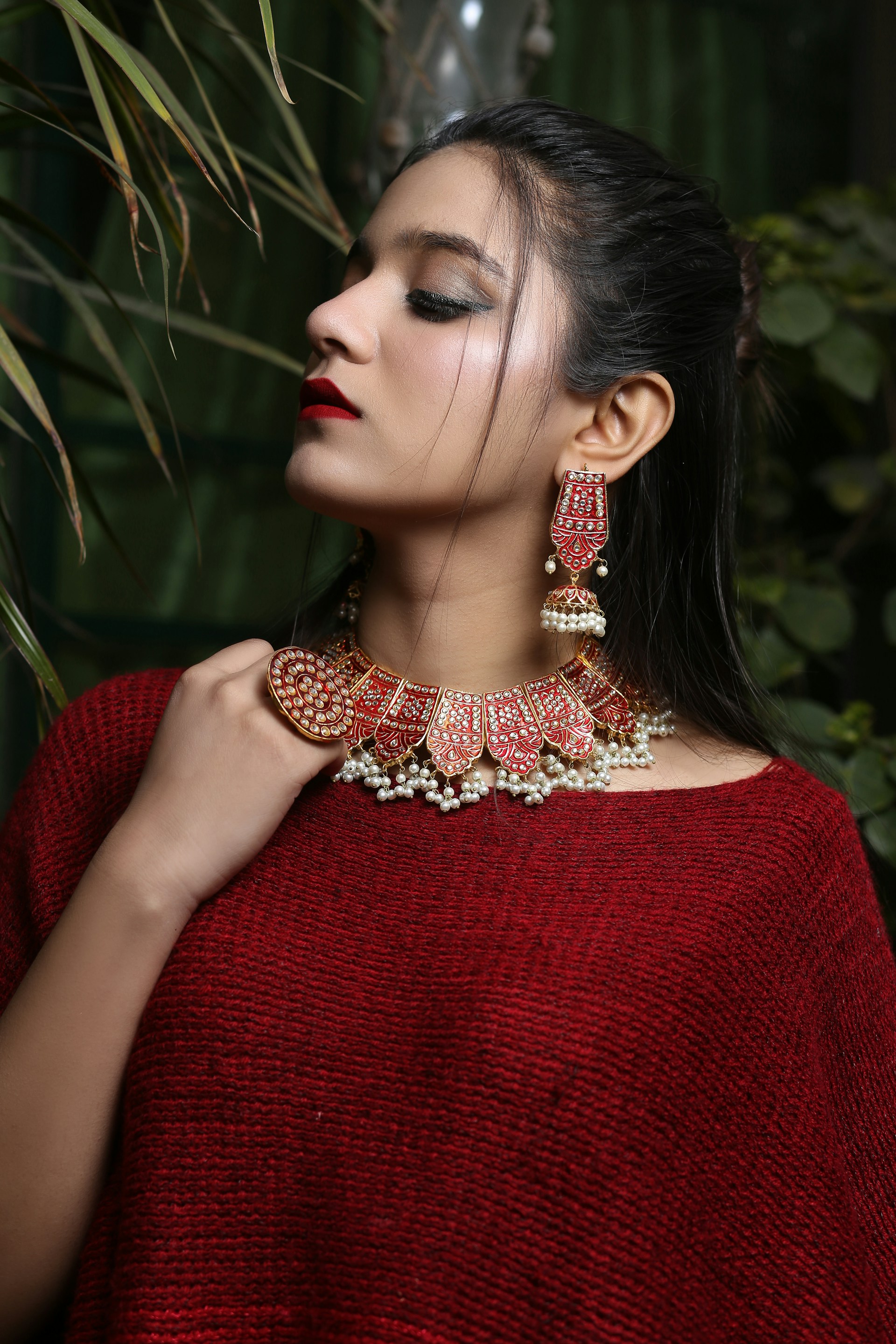 a woman wearing a red sweater and a pair of earrings