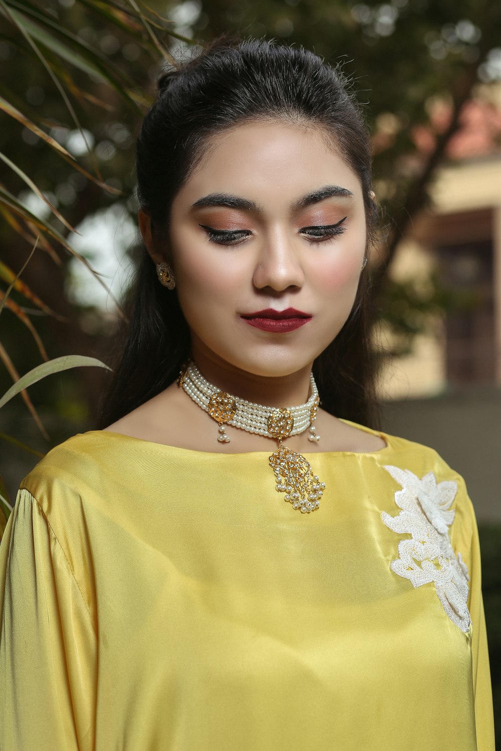 a woman wearing a yellow dress and a necklace