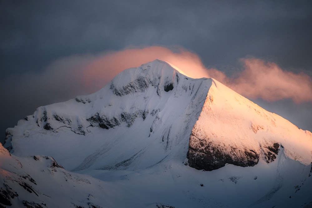 a mountain covered in snow under a cloudy sky