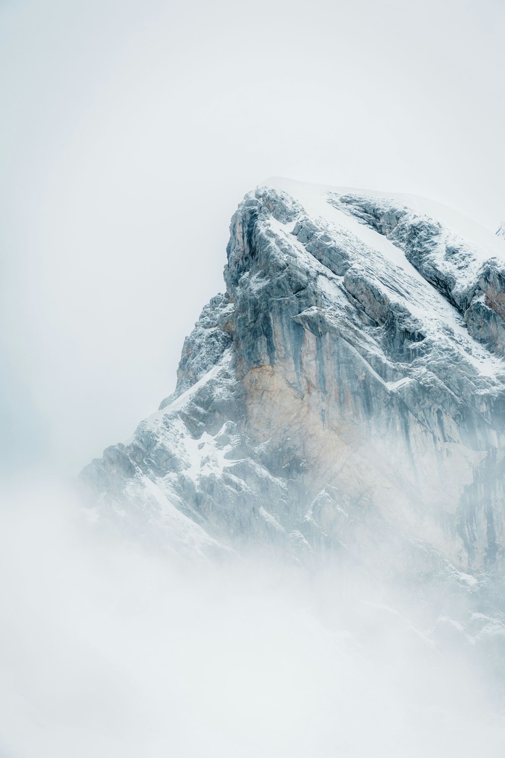 a large mountain covered in snow and clouds