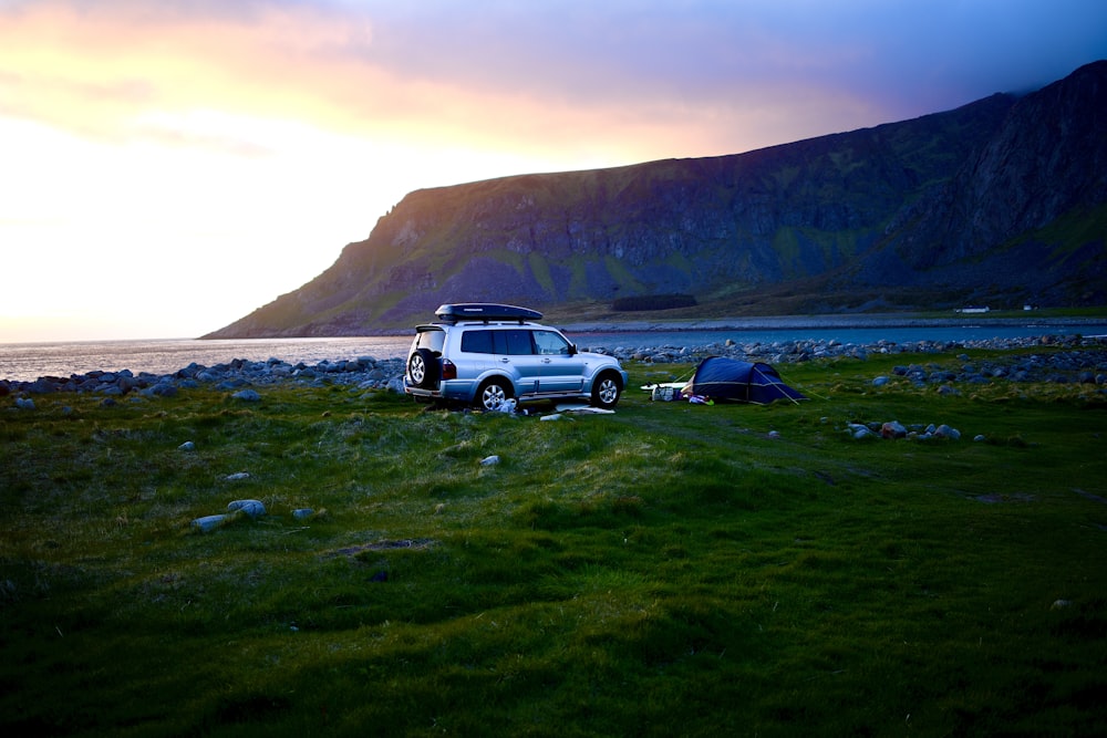 a car parked in a field next to a tent