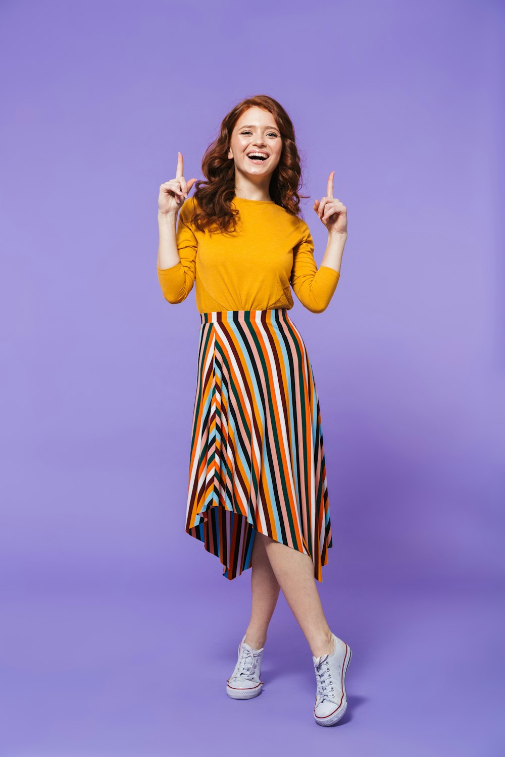 a woman in a yellow shirt and striped skirt