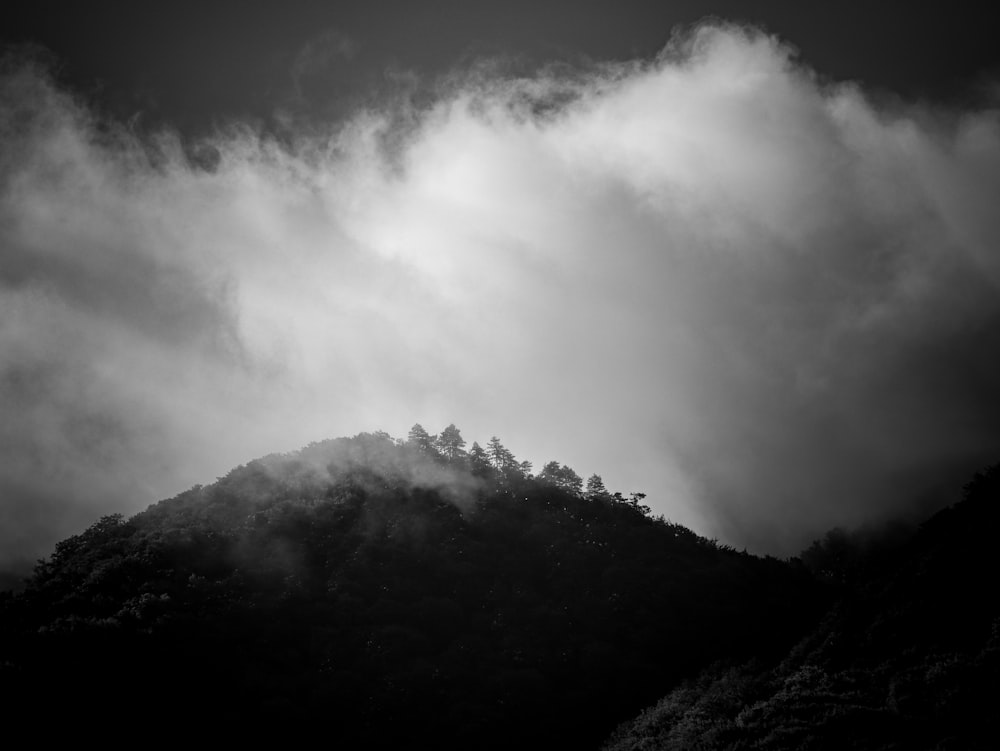 a black and white photo of a mountain covered in clouds