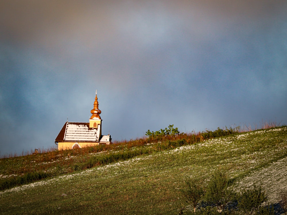 a small church on a hill under a cloudy sky