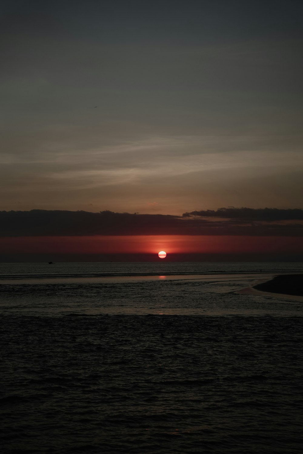 Il sole sta tramontando sull'oceano con una barca in lontananza