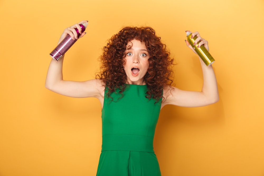 a woman in a green dress holding two hair dryers