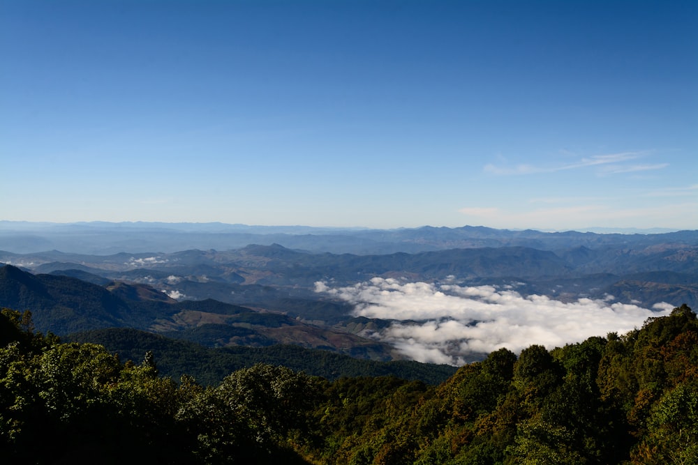 a view of the mountains and clouds from the top of a hill