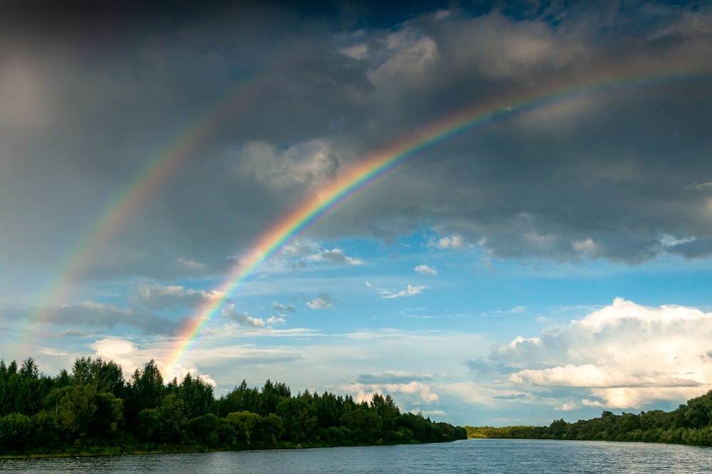 a rainbow is seen in the sky over a river