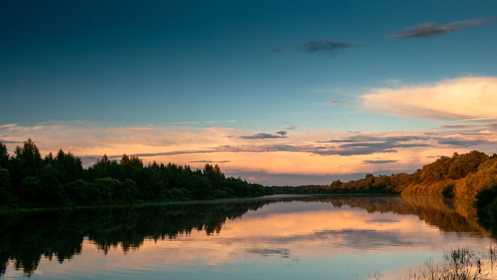 a body of water surrounded by trees and clouds