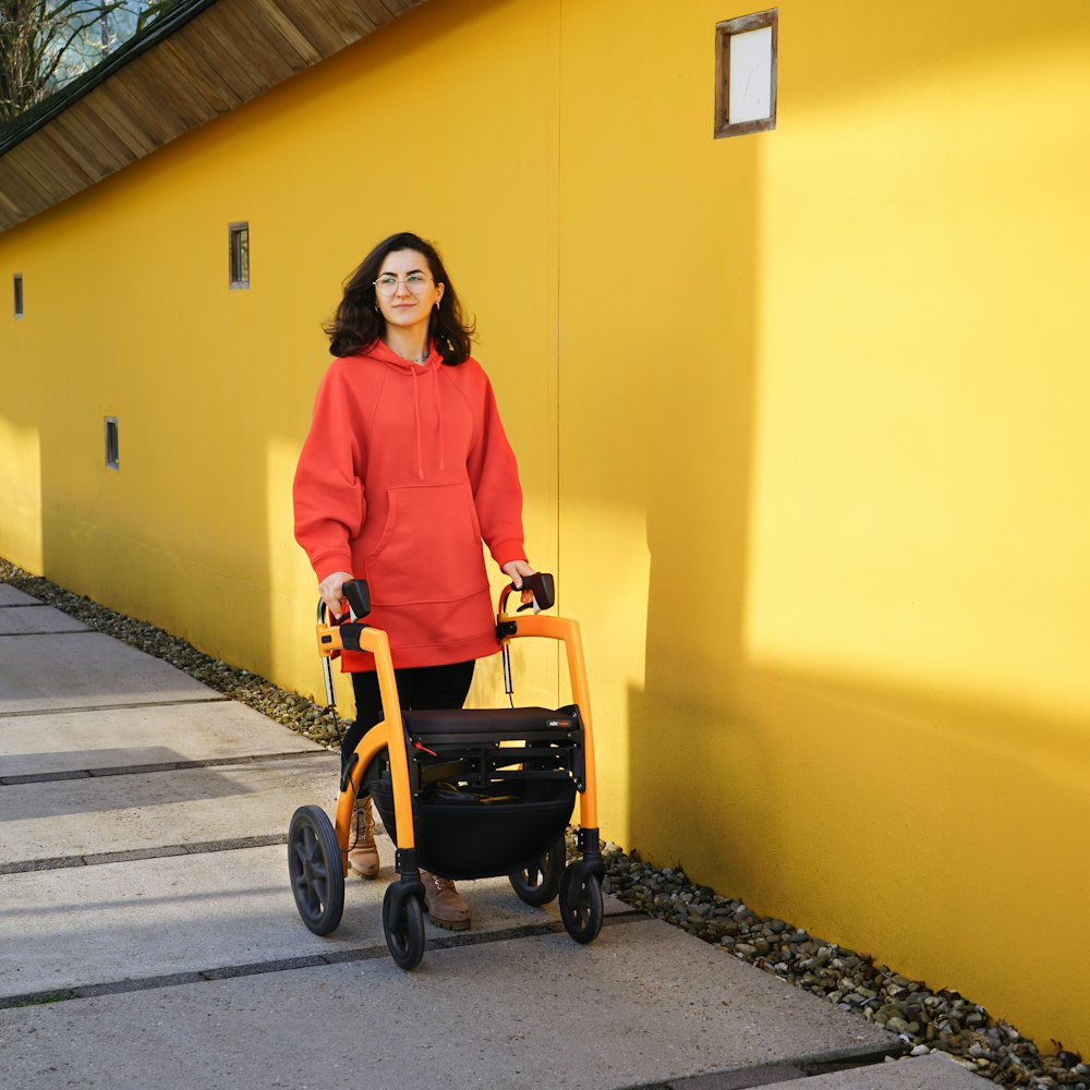 a woman in a red sweater is pushing a walker