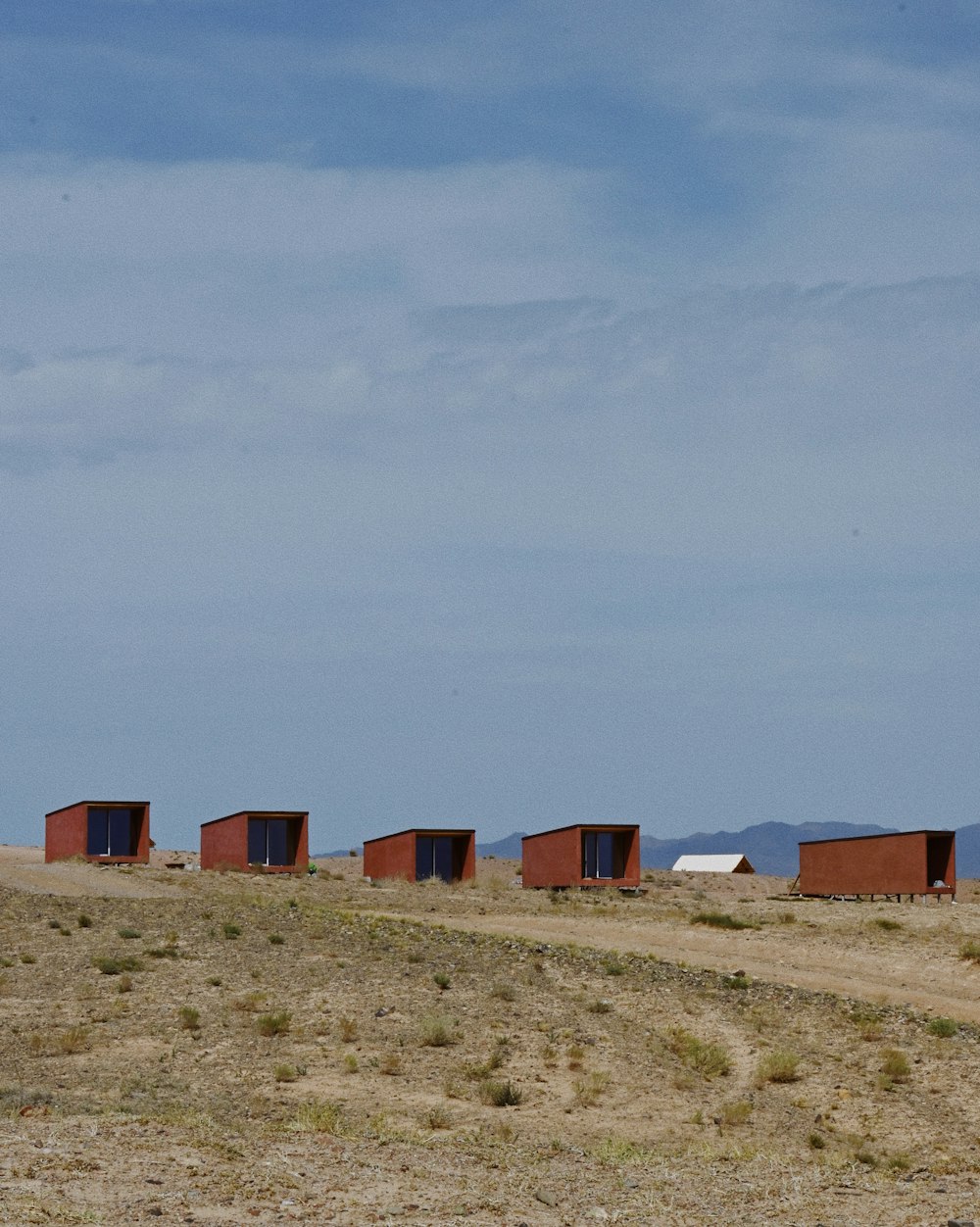 a row of red buildings sitting on top of a dry grass field