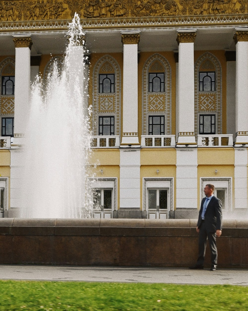 a man in a suit standing in front of a fountain