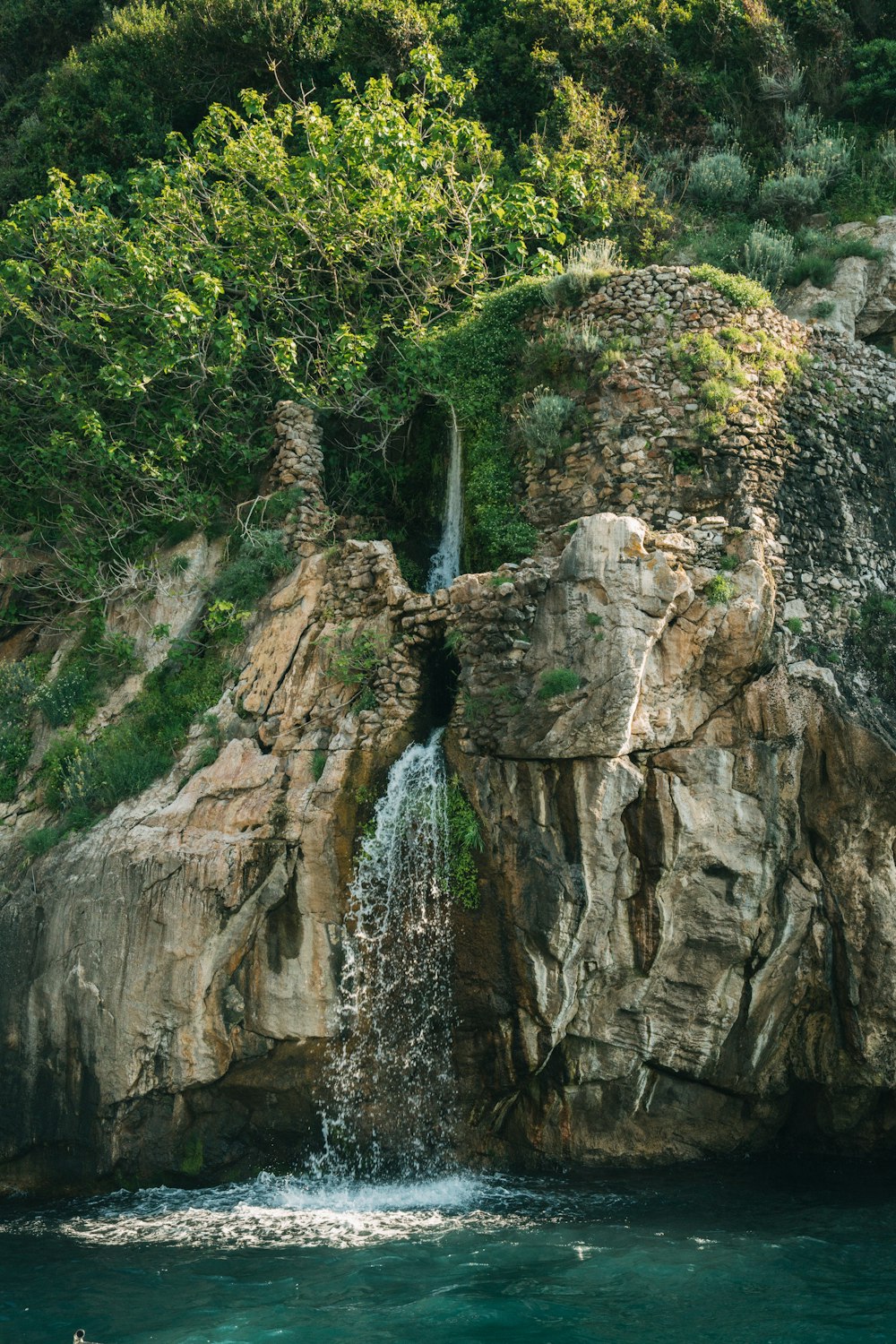 a waterfall is coming out of the rocks into the water