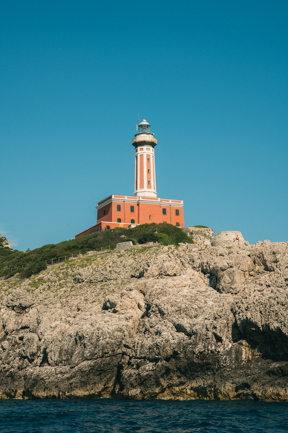 a red and white lighthouse on top of a cliff