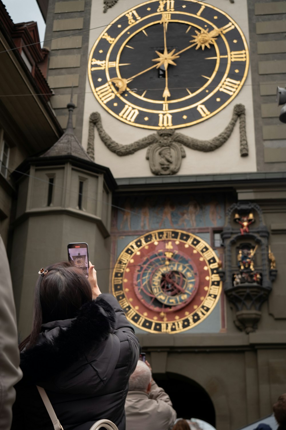 a woman taking a picture of a clock tower