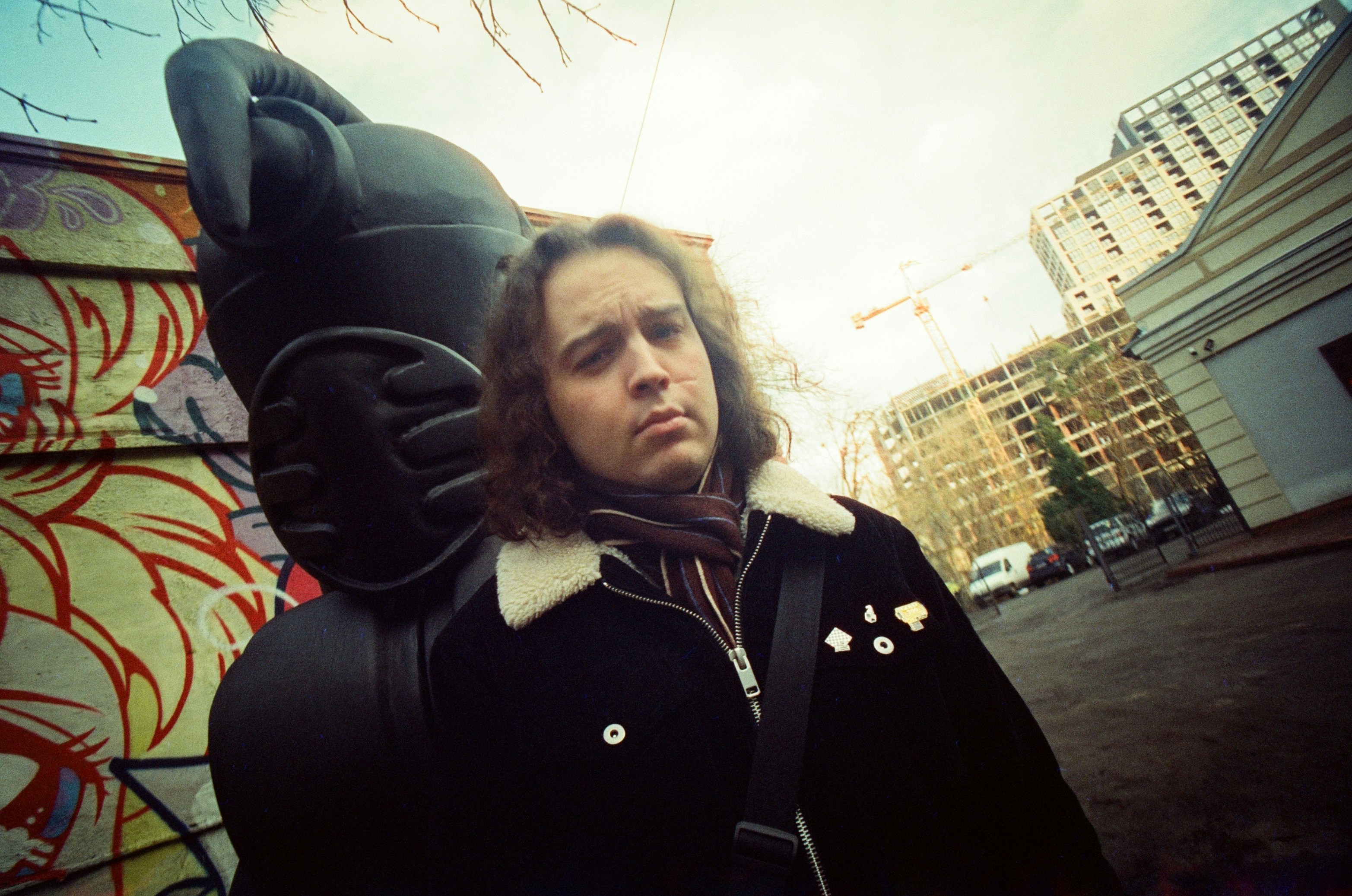 Seorang pria berdiri di depan dinding yang dipenuhi grafiti