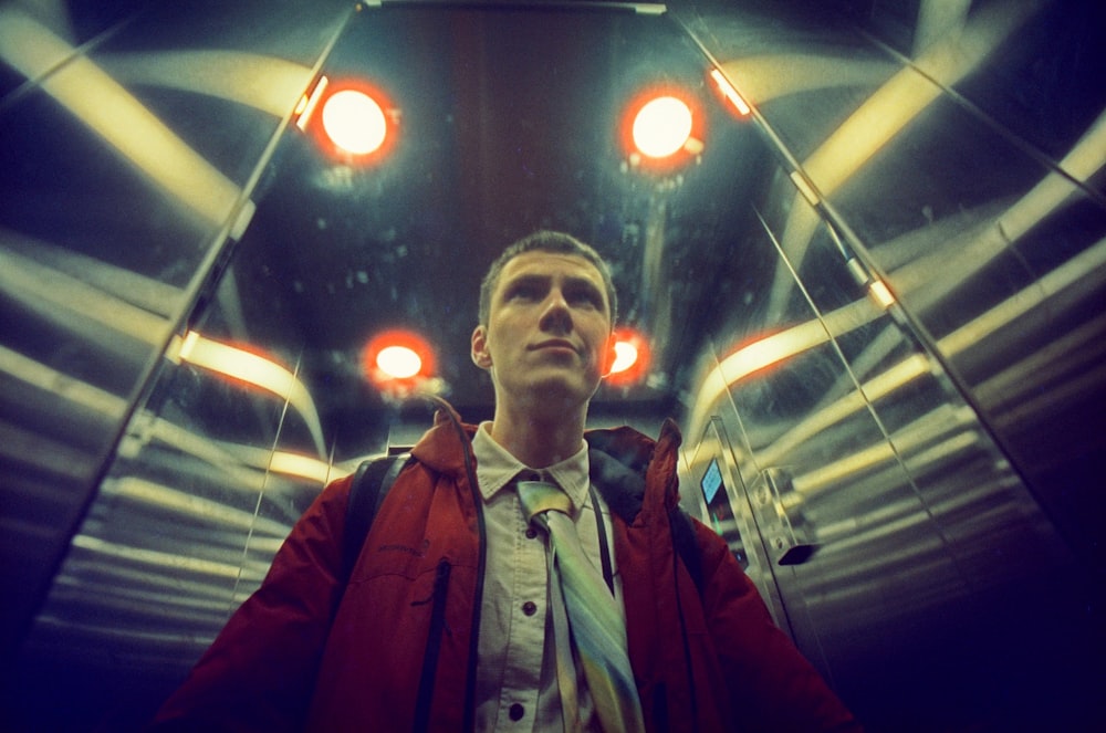 a man in a red jacket standing in a tunnel