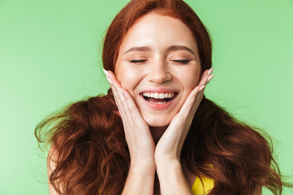 a woman smiling with her hands on her face