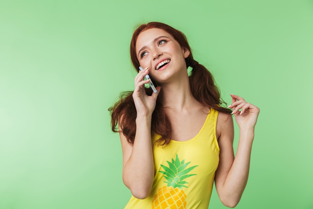 a woman in a yellow shirt talking on a cell phone