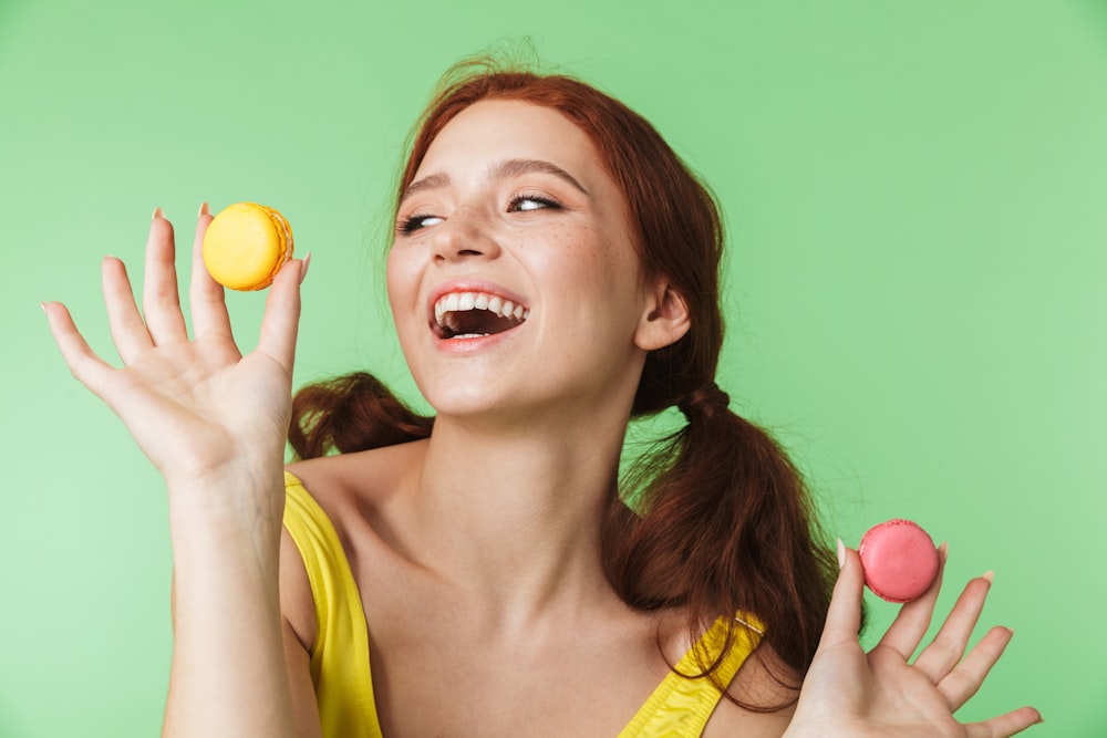 a woman in a yellow shirt holding a yellow and pink ball