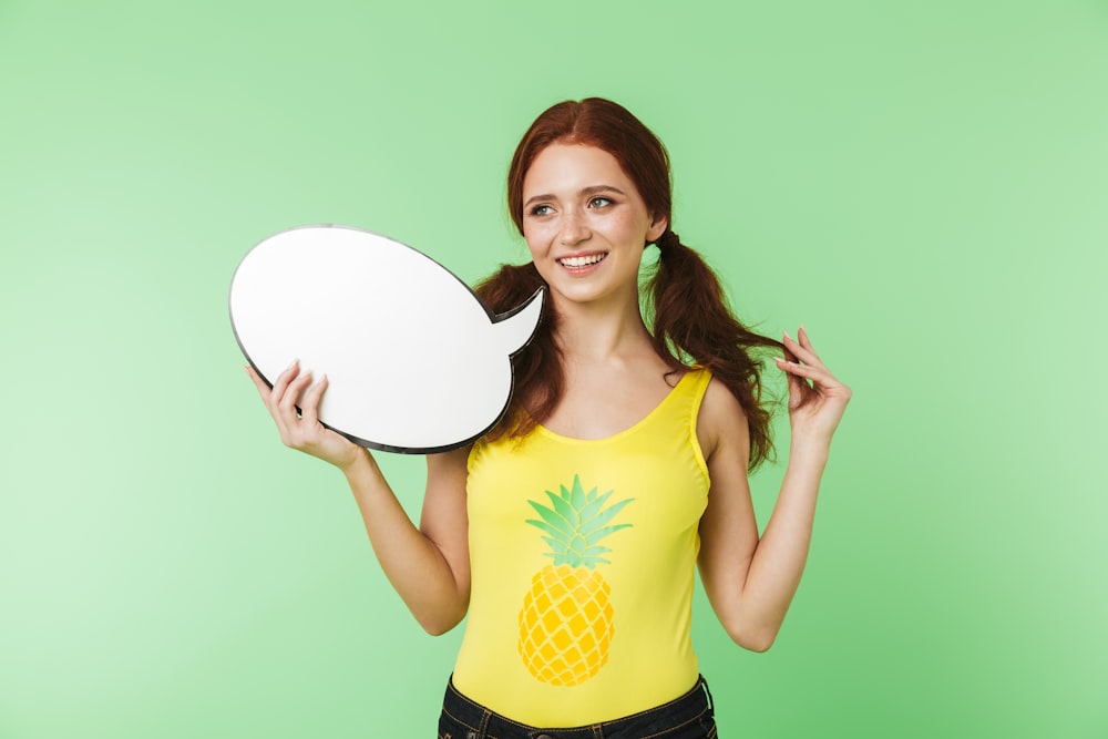 a woman in a yellow shirt holding a mirror
