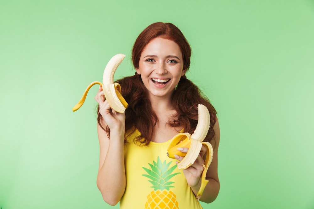a woman holding two bananas and a pineapple